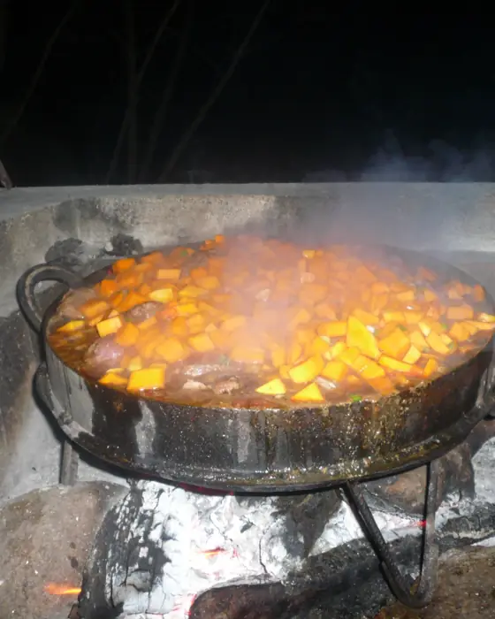 Comida cocinándose en un disco sobre el fuego, de noche.